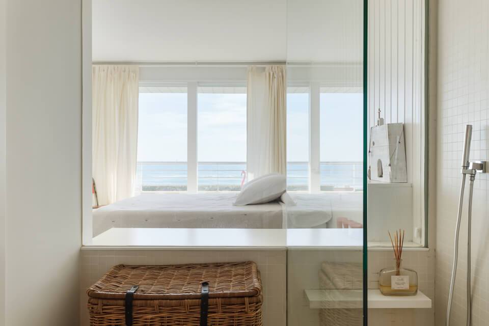 Baño con vistas al mar y pared de cristal que da al dormitorio