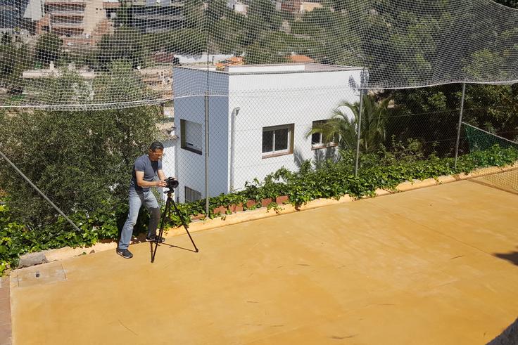 Ramon fotografiando a contraluz una casa de Sitges desde una pista de tenis.