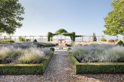 Portada de la galería villas. Fotografía de jardín de hierbas aromáticas rodeando una fuente con una pérgola de hiedra al fondo.